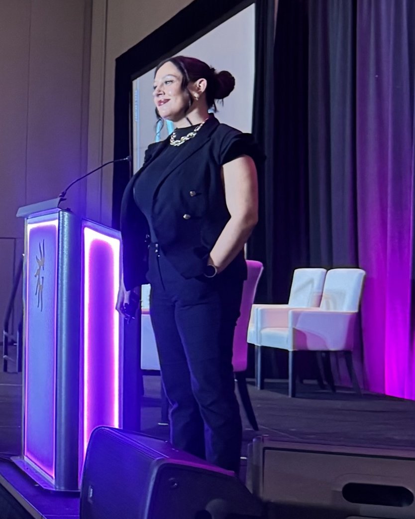 Steph Ketron on stage beside a lit podium